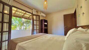 Quarto com uma cama grande, um guarda-roupa de madeira, uma luminária no teto e uma janela com cortinas.