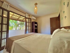 Quarto com uma cama grande, um guarda-roupa de madeira, uma luminária no teto e uma janela com cortinas.