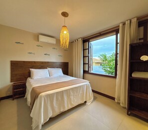 A hotel room with a bed, a hanging light fixture, a window with curtains, and a view of the outside.
