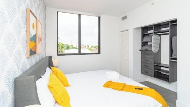 Una habitación de hotel moderna con una cama grande, un armario y una ventana con vistas a la ciudad.