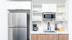 A modern kitchen with a stainless steel refrigerator, a microwave, and a coffee maker on the countertop.
