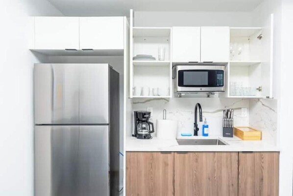 A modern kitchen with a stainless steel refrigerator, a microwave, and a coffee maker on the countertop.