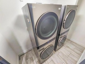 A pair of LG wall-mounted washing machines in a room with tiled flooring.