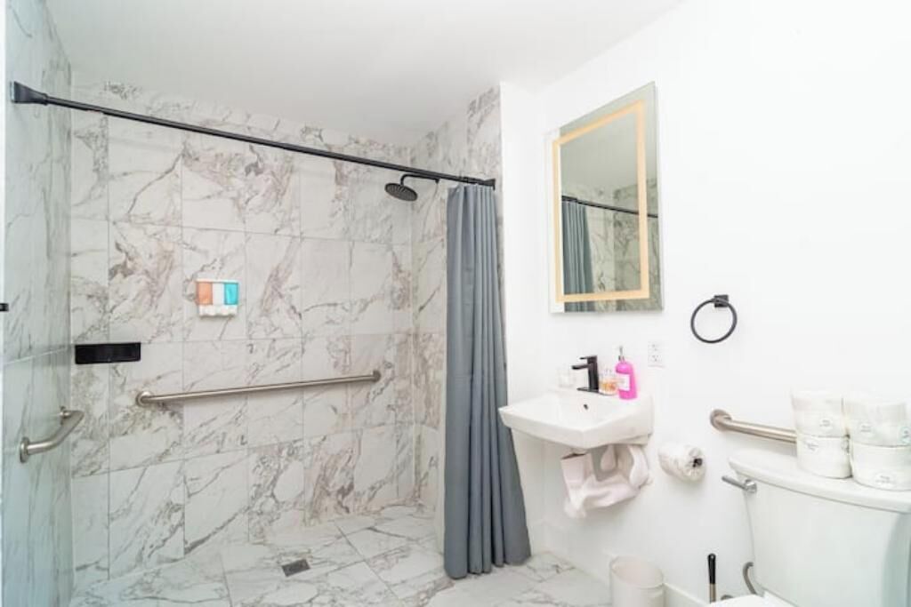 A bathroom with a shower, a sink, a toilet, and a mirror.