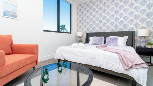 Une chambre à coucher moderne avec un lit, une table basse ronde en verre et un canapé.