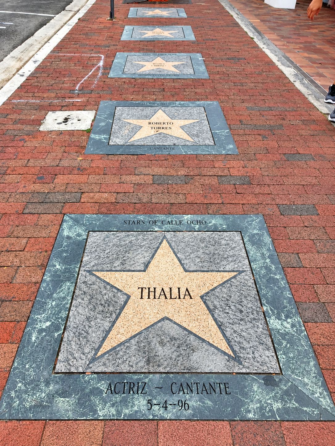 Ein Bürgersteig mit einer Reihe sternförmiger Plaketten, jede mit einem Namen und einem Datum.