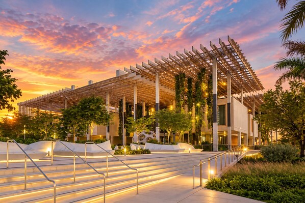 A modern building with a wooden pergola, outdoor stairs, and greenery.