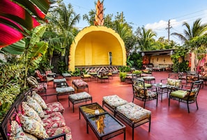 An outdoor seating area with wicker furniture and a yellow arch structure.
