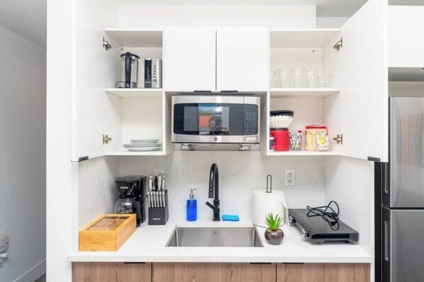 A compact kitchen with a microwave, sink, and various kitchen items.