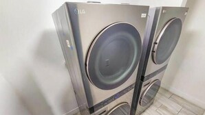 Dos lavadoras LG empotradas en la pared de un cuarto de lavado con piso de baldosas.