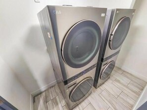 To LG vaskemaskiner, fastgjort på væggen, i et rum med flisegulv.