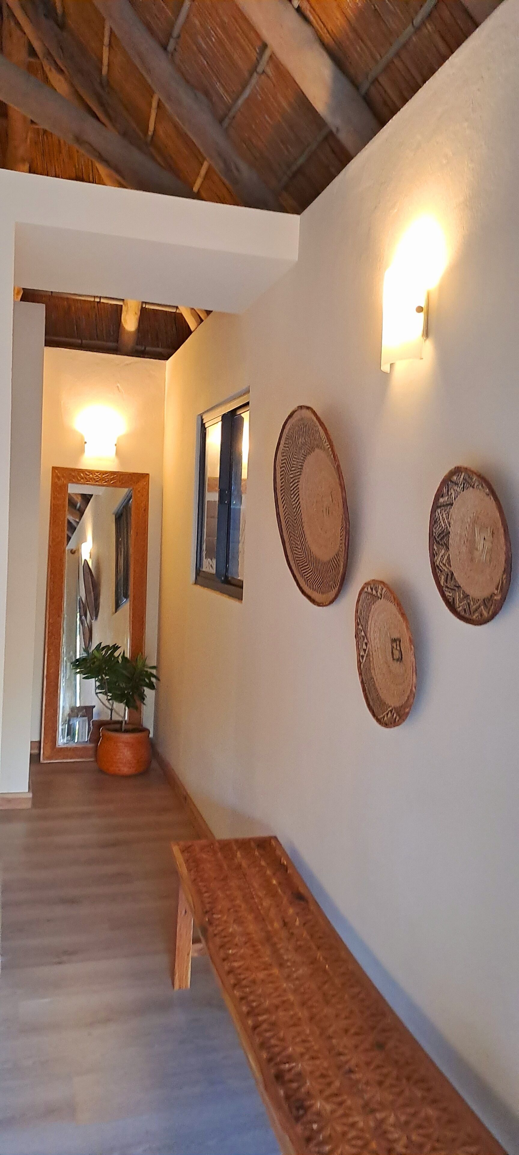 A hallway with a wooden bench, a potted plant, and wall-mounted decorative plates.