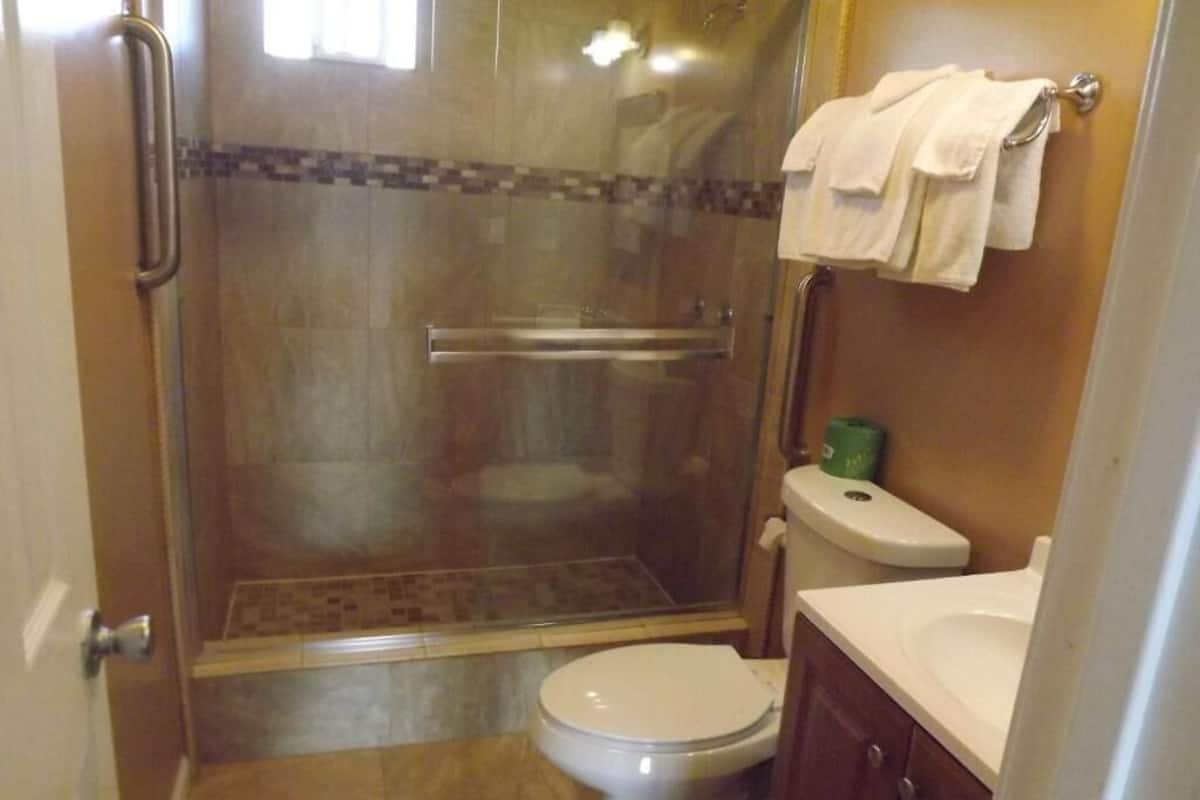 Une salle de bain avec une douche à parois de verre, des toilettes et un lavabo équipé d’un porte-serviettes.