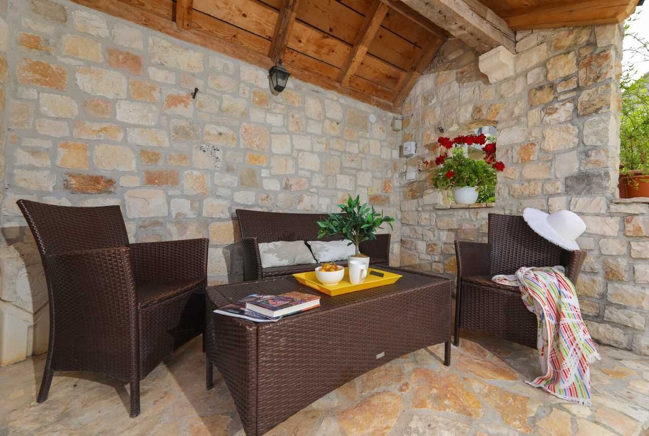 Un espace extérieur aménagé avec des murs en pierre, des meubles en osier et un pot de fleurs.