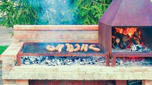 Un barbecue avec des saucisses en train de cuire sur une plateforme en briques.