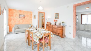 Un coin repas avec une table dressée pour quatre personnes, un canapé et un meuble en bois agrémenté d’objets décoratifs.