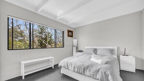 Una camera da letto moderna con un'ampia finestra, un letto, un comodino, una panca e un termosifone.