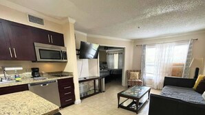 A compact living space with a kitchenette, a dining area, and a seating area with a sofa and a chair.