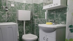 A bathroom with a toilet, a sink, and a shower. - Tiny Romantic Flat in the Centre (Belgrade)