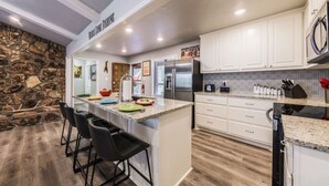 Una cocina moderna con armarios blancos, encimeras de granito y una pared de acento de piedra.