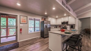 Una cocina moderna con armarios blancos, un refrigerador de acero inoxidable y una isla grande con taburetes de bar.