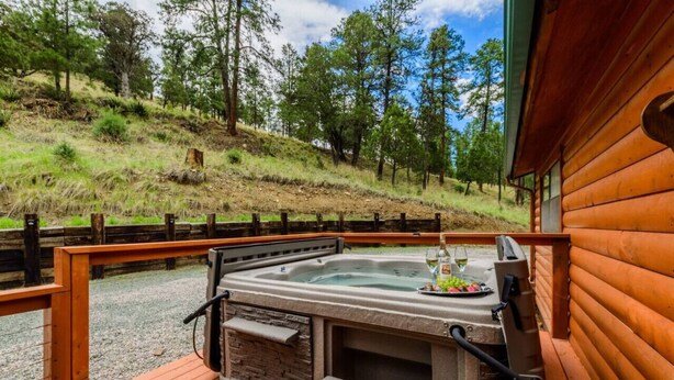 Un jacuzzi en una terraza de madera con vistas a una ladera boscosa.