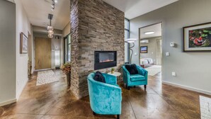 A modern living room with a stone fireplace, teal armchairs, and a large window. - This Is It -Gorgeous Southwest Modern Luxury! (Alto)