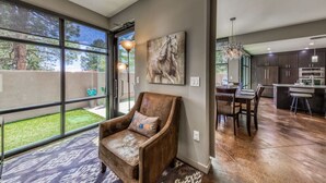 A modern interior with a large sliding glass door leading to a backyard, a dining area with a chandelier, and a kitchen with dark cabinetry. - This Is It -Gorgeous Southwest Modern Luxury! (Alto)