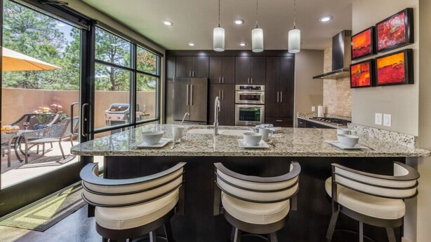 A modern kitchen with dark cabinets, a granite countertop, and three bar stools. - This Is It -Gorgeous Southwest Modern Luxury! (Alto)