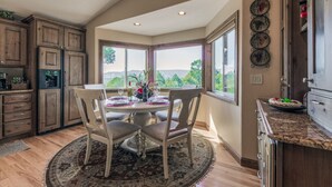 A dining area with a round table, chairs, and a view of the outdoors. - Wine & Wilderness: MTN Luxe Chalet/ Hot Tub/ Views (Ruidoso)