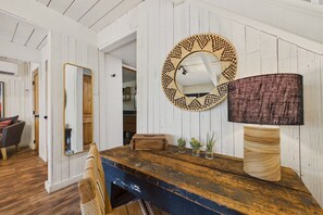Un comedor rústico con una mesa de madera, un espejo tejido y una lámpara con textura.