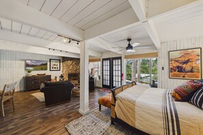 Un dormitorio amplio con una cama grande, chimenea, televisor y vistas al exterior.