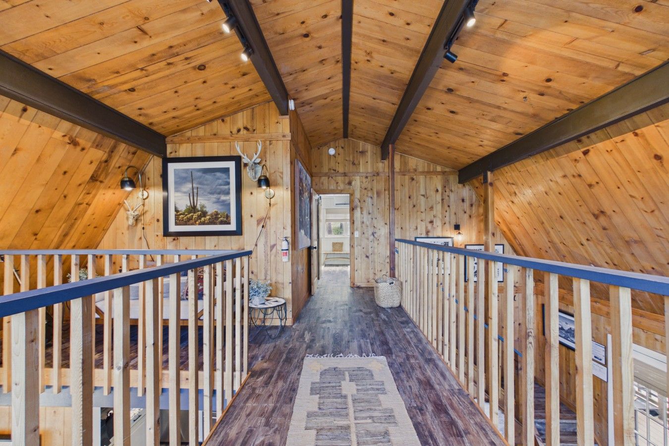 A wooden interior with a central staircase, railings, and a patterned floor.