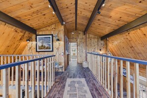 Un interior de madera con una escalera central, barandillas y un piso con diseño.