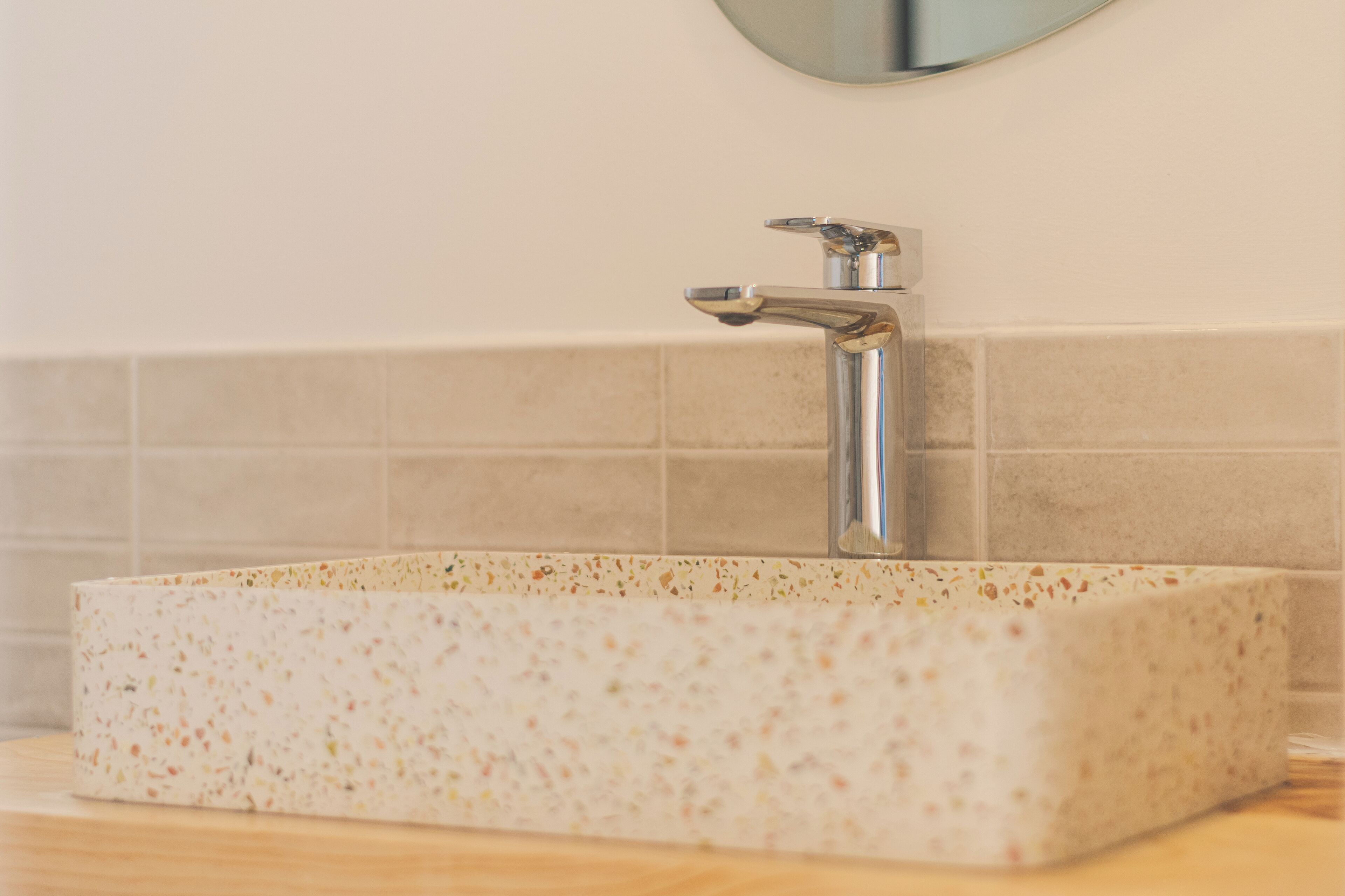 A rectangular sink with a speckled countertop, a chrome faucet, and a mirror above it.
