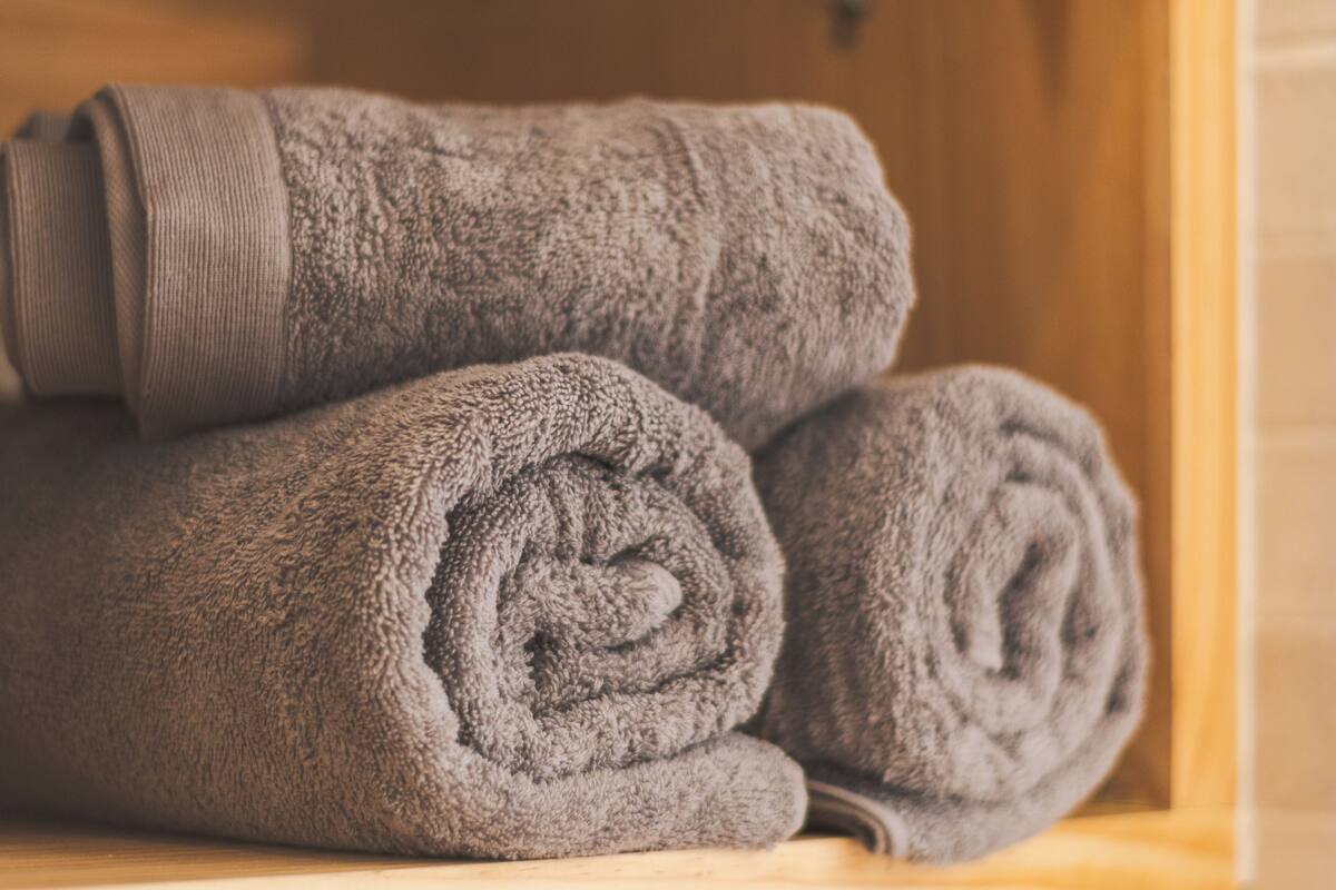 A wooden cabinet with folded gray towels.