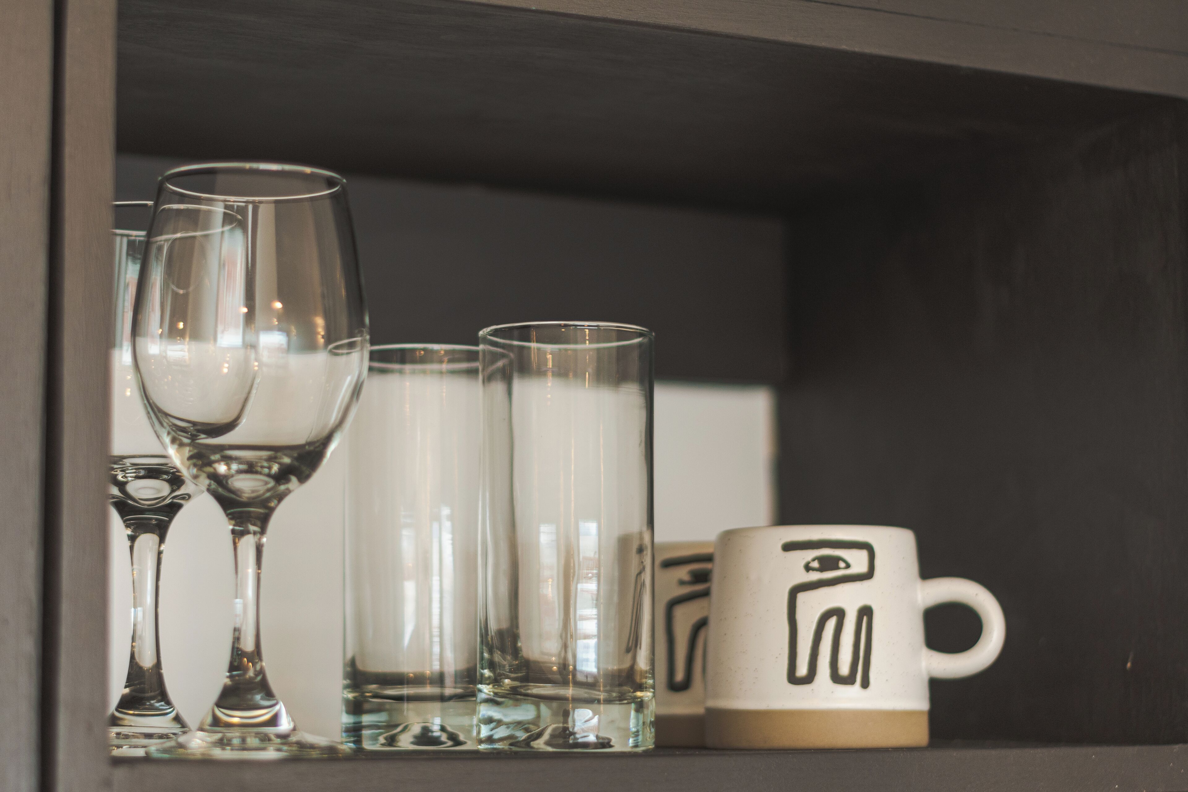 A shelf with clear glassware and a ceramic mug.