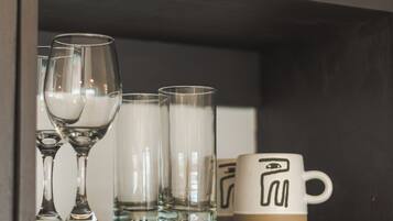 Una repisa con vasos de vidrio transparente y una taza de cerámica.