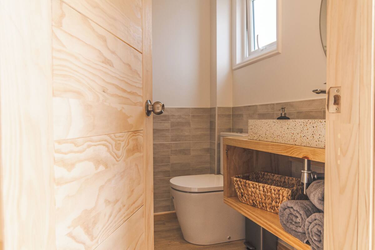 A bathroom with a wooden vanity, a white toilet, and a towel rack.
