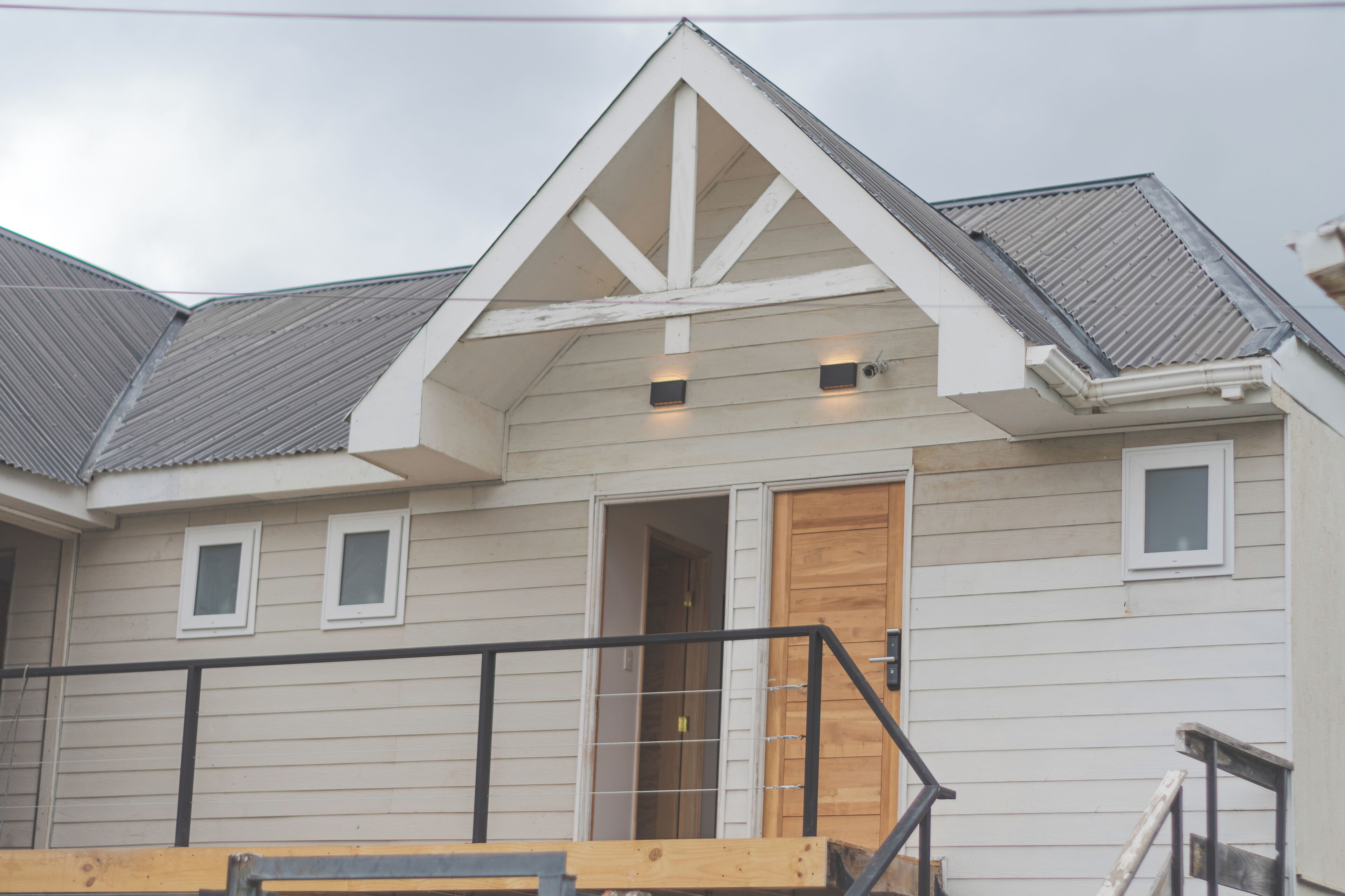 A two-story house with a gabled roof, a wooden front door, and a small porch with a railing.