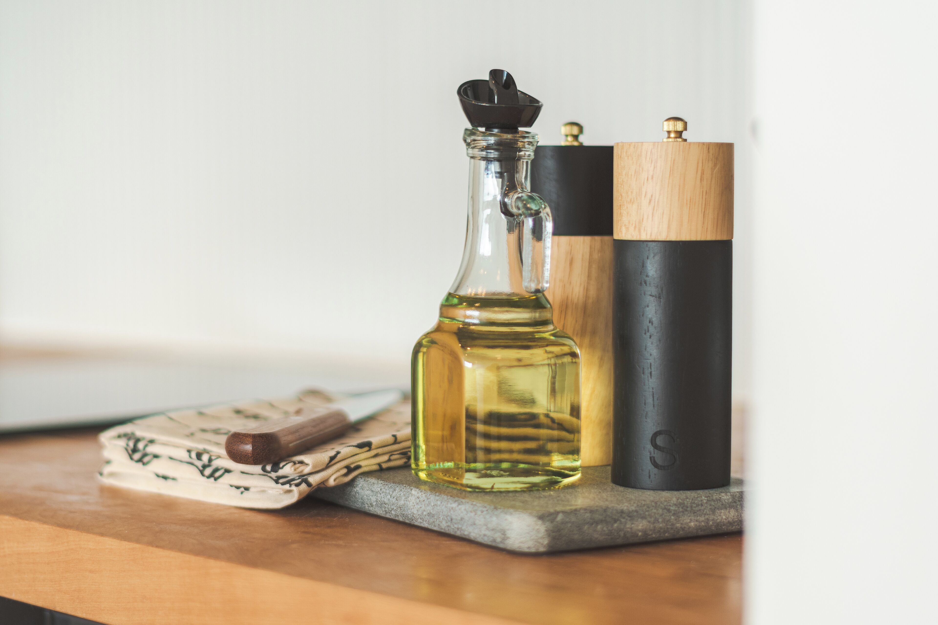 A wooden table with a glass bottle, a wooden block, and a black container.