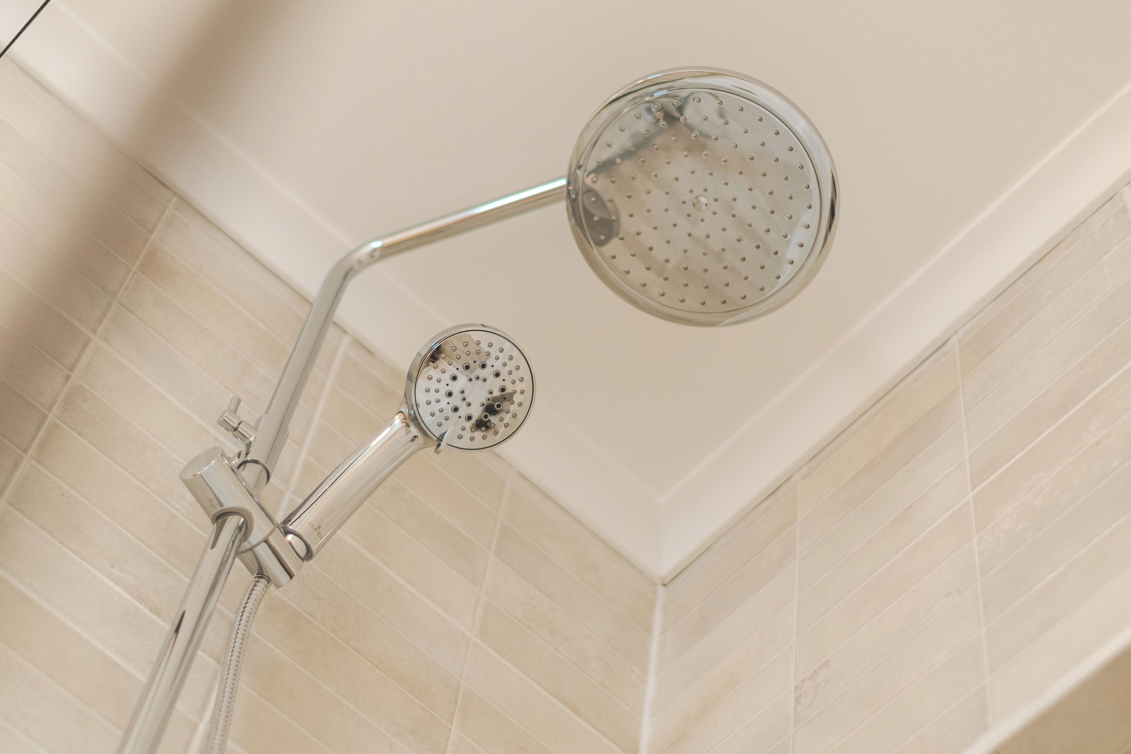 A shower with a handheld showerhead and a fixed showerhead.