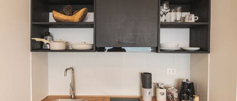 Una cocina con encimera de madera, pileta de acero inoxidable y alacenas negras.
