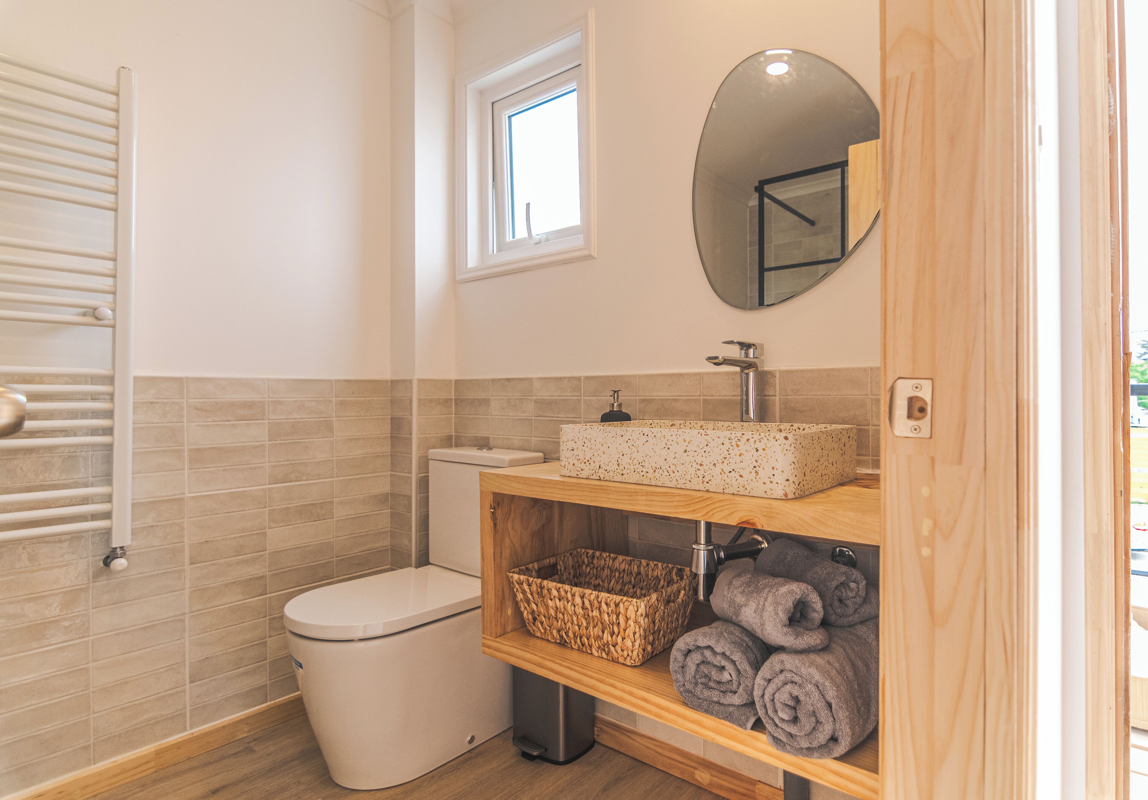 Une salle de bain comprenant des toilettes, un lavabo avec un miroir, un porte-serviettes et une fenêtre.