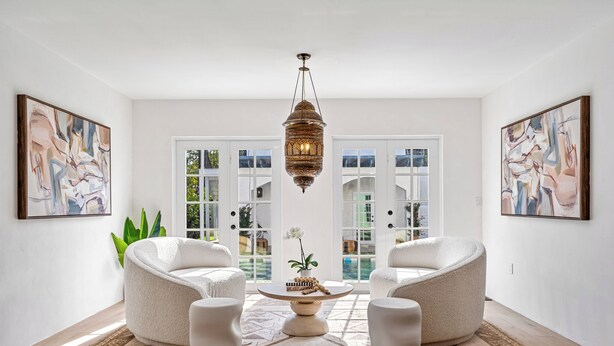 A spacious living room with two white armchairs, a round coffee table, and a hanging lantern.