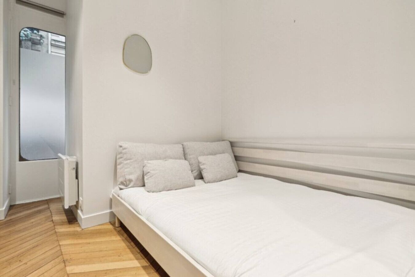 A bedroom with a single bed, a radiator, and a window.