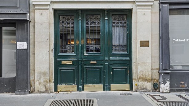Una porta verde a due battenti con il numero "3" sopra, che indica il numero civico dell'edificio.