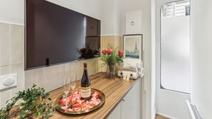 Una cucina moderna con un piano di lavoro in legno, una bottiglia di vino, bicchieri e un vassoio con petali di rosa.