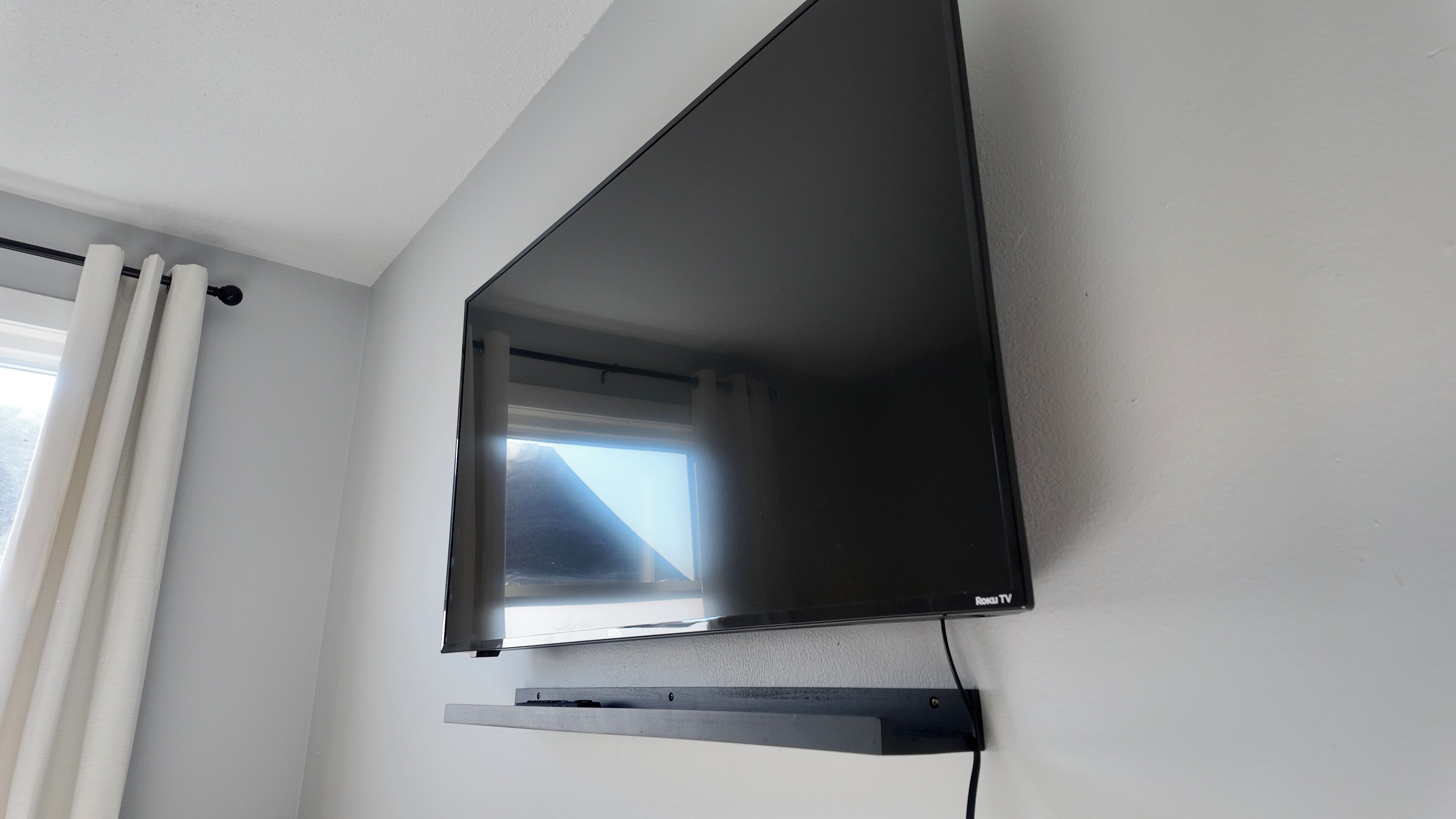 En platt-TV som är monterad på en vägg, med en kabelbox placerad under den.