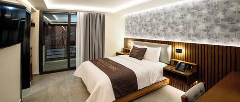 Una habitación de hotel moderna con una cama grande, un escritorio y un televisor.